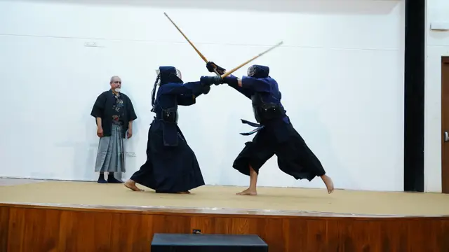 Kendo demonstration on stage: a men strike under the referee's eye